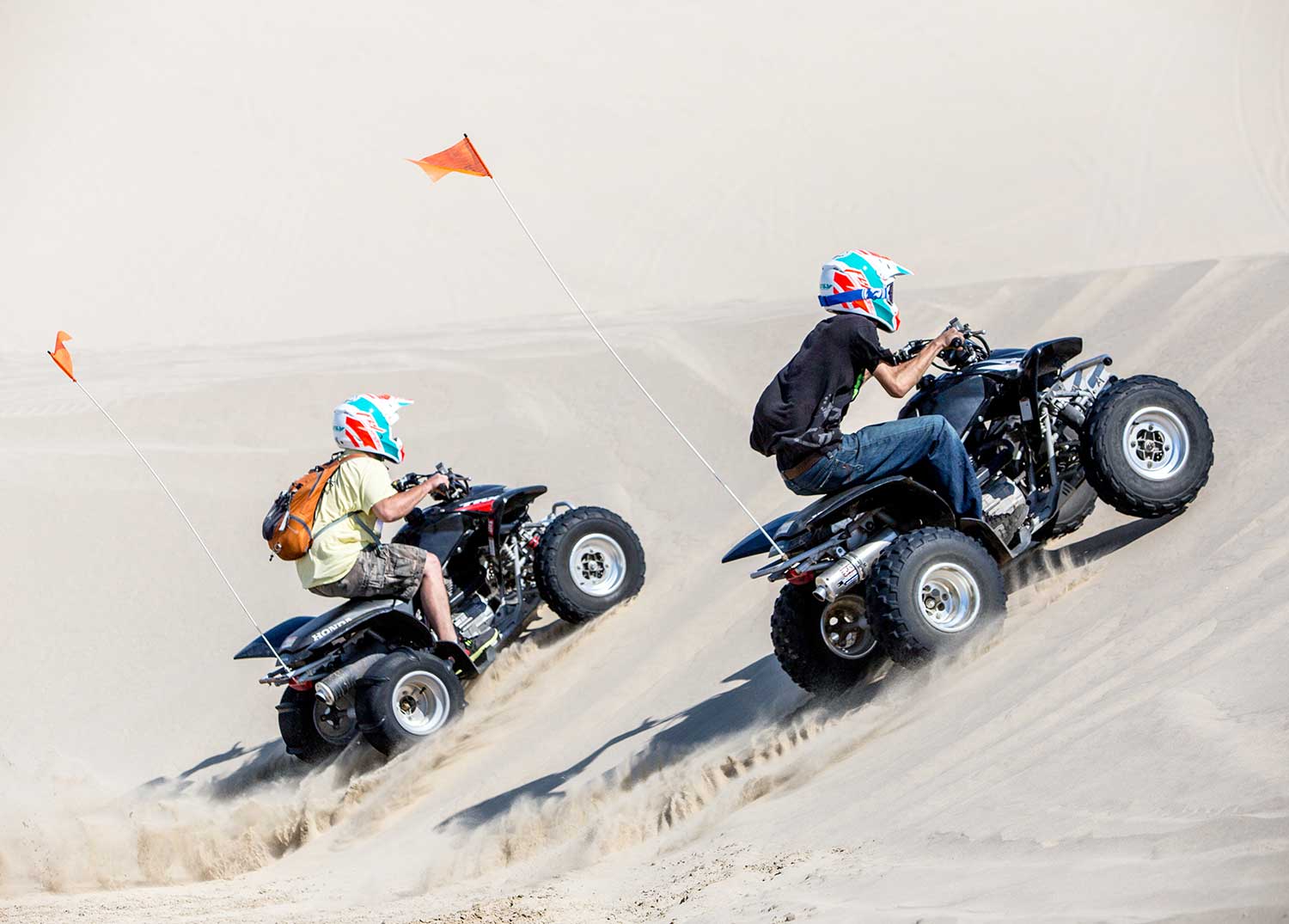 ATV renters climbing a dune on their quads